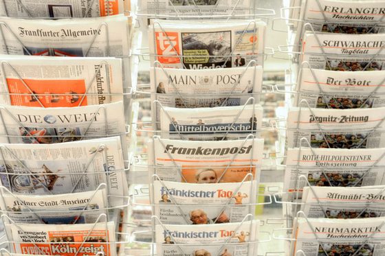 Diverse Tageszeitungen stehen in Regal.
