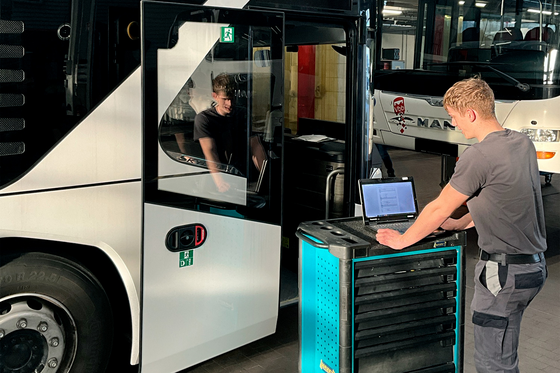 Der Kraftfahrzeugmechatroniker arbeitet IT-unterstützt an einem MAN-Bus.