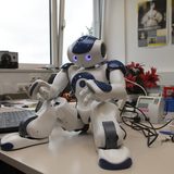 Ein kleiner Roboter sitzt auf einem Schreibtisch.