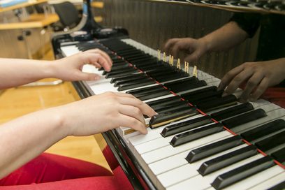 Zwei Hände sind sichtbar, die auf einem Klavier spielen.