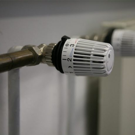 Das manuelle Thermostat einer Heizung zeigt auf die Stufe 3,5. Ein zweites Heizungsthermostat ist unscharf rechts daneben zu erkennen.