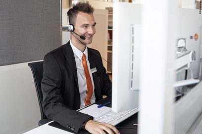 Ein Mann sitzt mit Kopfhörern vor einem Computerbildschirm in einer Videokonferenz.