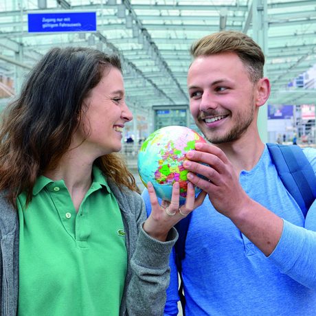 Ein Mann und eine Frau halten gemeinsam einen kleinen Globus in den Händen. 