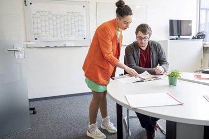 Eine Berufsberaterin und ein Schüler schauen sich zusammen ein Heft an.