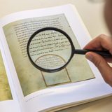 Detailaufnahme des Betrachtens einer mittelalterlichen Schrift mit einer Lupe. (Foto: Swen Reichhold)