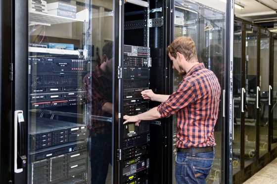 Ein Mann zieht eine Festplatte aus einem Serverterminal.