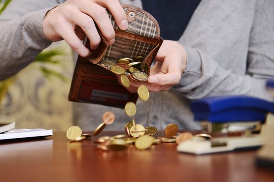 Viele verschiedene Geldmünzen fallen aus einem Geldbeutel auf einen Tisch. (Foto: Julien Fertl)