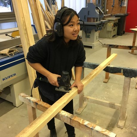 Hanni Nguyen bearbeitet Holz mit einer Stichsäge.