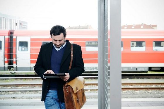 Ein Mann mit Tablet-Computer steht am Bahnsteig.