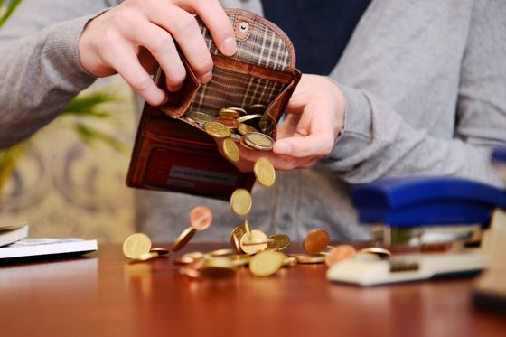 Kleingeld wird aus seinem Geldbeutel auf einen Tisch gekippt. (Foto: Julien Fertl)