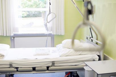 Ein Krankenhausbett in einem Krankenzimmer vor einem Fenster