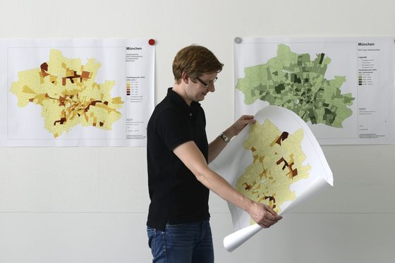 Ein Mann rollt ein Plakat auf dem eine Landkarte abgebildet ist für einen Vortrag aus.