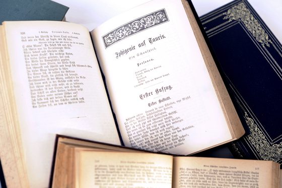 Zwei alte Bücher aus dem Archiv liegen aufgeschlagen da. In alter Schrift steht auf dem einen "Ephigenie auf Tauris".