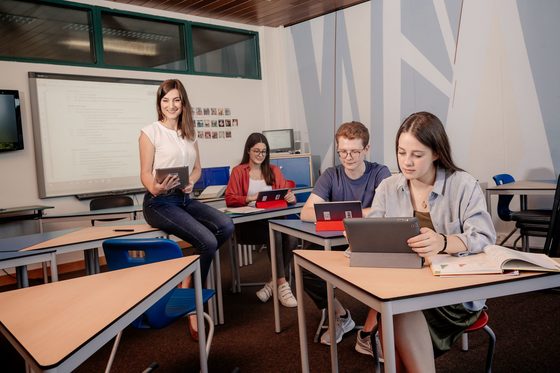 Eine Lehrerin und drei SchülerInnen befinden sich in einem Unterrichtsraum und arbeiten mit Tablet-Computern.