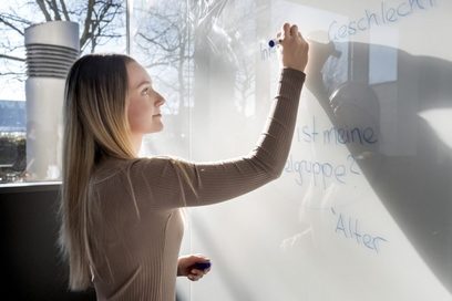Eine junge Frau schreibt mit dem Stift eine Mindmap auf das Whiteboard.