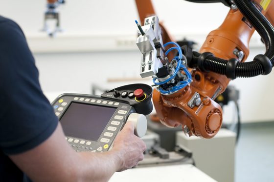 Männerhände halten die Steuerung eines Industrieroboters (Foto: Steffen Kirschner und Sebastian Mildenberger | Bundesagentur für Arbeit)