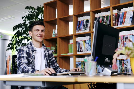 Ein junger Mann sitzt an einem Computer in einem BIZ und informiert sich über Jobmöglichkeiten.