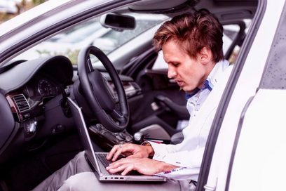 Mann sitzt im Inneren eines Autos und nimmt einige Einstellungen am Steuergerät vor mithilfe seines Laptops. Foto: André Braun
