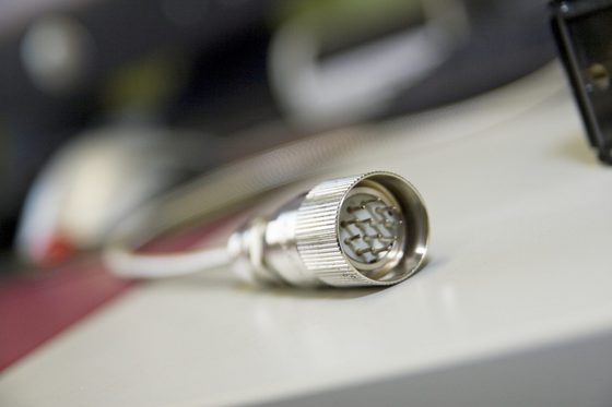 Ein Sensorkopf mit LED Laserbeleuchtung als OEM-Kopf mit Verbindungselement liegt auf einer weißen Unterlage. (Foto: Bundesagentur für Arbeit)