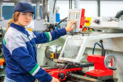 Eine junge Frau arbeitet an einer CNC-Fräsmaschine.