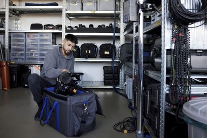 Ein junger Mann packt eine Kamera in eine Packtasche.