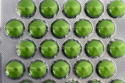Aufnahme von einem silbernen Tablettenblister mit grünen Pillen. An der Seite der Verpackung ist das Verwendungsdatum eingeprägt.