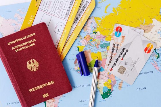 Blick auf verschiedene Reiseutensilien wie etwa einen Reisepass, eine Weltkarte, FLugtickets und Kreditkarten. (Foto: Julien Fertl)