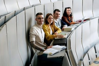 Vier Jugendliche sitzen in einem Hörsaal und arbeiten.