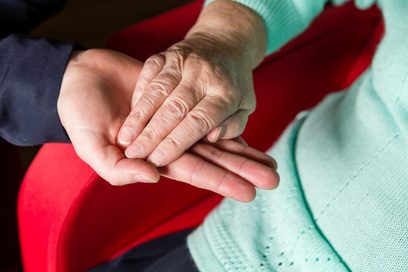 Eine junge Hand hält die Hand einer älteren Person.