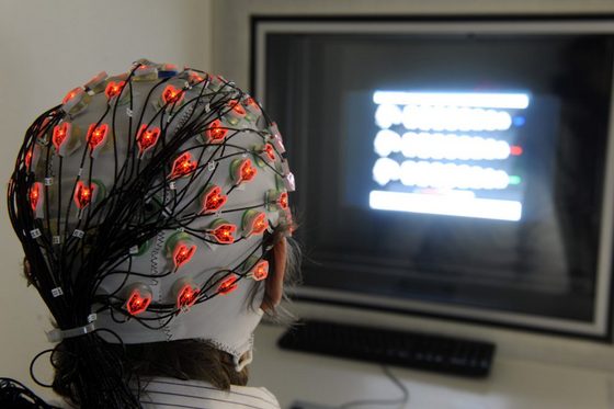 Rückenansicht einer Probandin am Bildschirm, deren Gehirnströme gemessen werden.