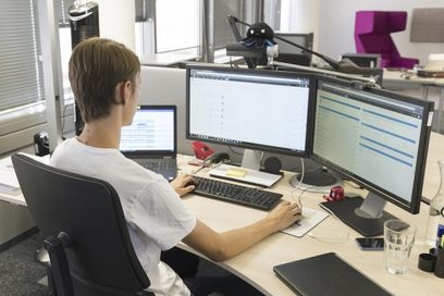 Ein junger Mann arbeitet an einem Computer mit zwei Bildschirmen. (Foto: Annette Kradisch | Bundesagentur für Arbeit)