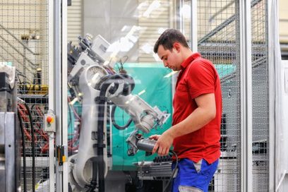 Ein junger Mann steuert mit einer Fernbedienung einen Roboter. (Foto: Katharina Kemme)