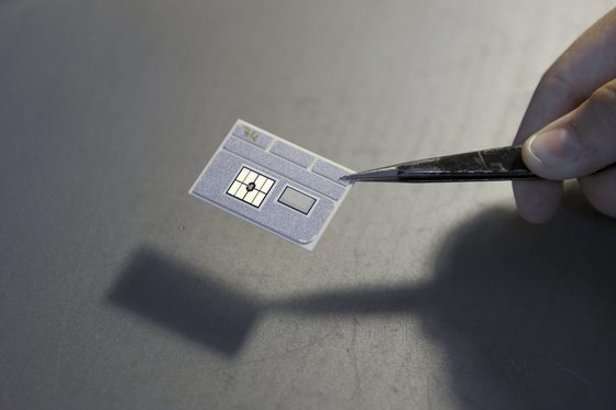 Ein Mikrochip der mit einer Pinzette gehalten wird.