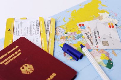 Blick auf verschiedene Reiseutensilien wie etwa einen Reisepass, eine Weltkarte, Flugtickets und Kreditkarten.
