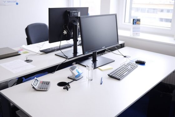 Zwei Schreibtische, auf denen Computer und eine Auswahl an anderen Dingen fürs Büro stehen.