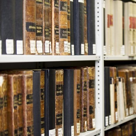 Seitliche Aufnahme einer Regalreihe von weißen Metallregalen mit antiken Büchern, die systematisch gekennzeichnet wurden. (Foto: Bundesagentur für Arbeit)