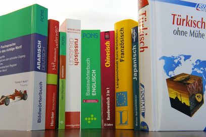 Mehrere Wörterbücher in den Fremdsprachen spanisch, chinesisch, russisch, französisch, italienisch, japanisch, arabisch, englisch und türkisch stehen nebeneinander.