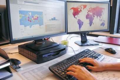 Hände liegen auf einer Computertastatur vor einem Bildschirm, auf dem eine Projektübersicht angezeigt wird.