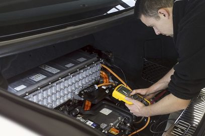 Ein KFZ-Mechatroniker der Fachrichtung System- und Hochvolttechnik arbeitet an einem Fahrzeug.