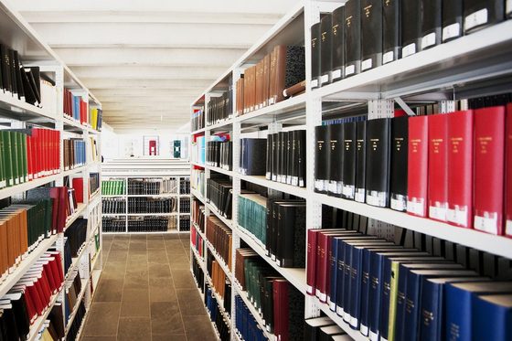 In einem Archiv sind mehrere Regale mit ledergebundenen Büchern zu sehen.