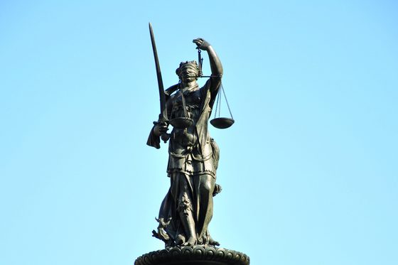 Aufnahme einer Justitia-Statue vor blauem Himmel.