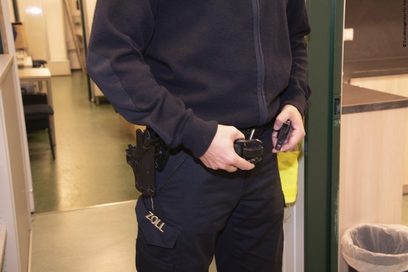 Ein junger Mann zieht sich einen Gürtel mit einer Pistolenhalterung an.