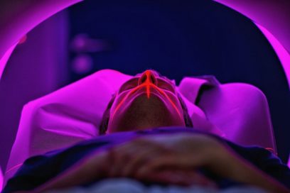 Das Bild zeigt eine Person in einem MRT liegend. Die Arme sind über dem Bauch verschränkt und die Augen geschlossen. Beleuchtet wird das MRT durch eine magentafarbene Lampe. Foto: Hans-Martin Issler