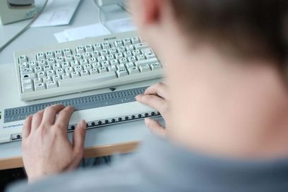 Sehbehinderter Mann am Schreibtisch mit Braille-Tastatur (Foto: Martin Rehm)