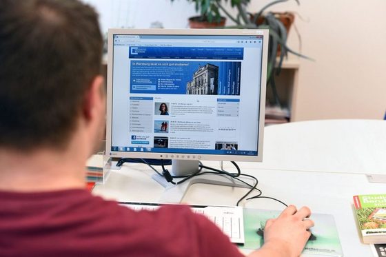 Ein Mann sitzt an einem PC und recherchiert auf der Webseite einer Universität. (Foto: Katharina Kemme)