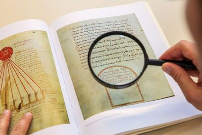 Detailaufnahme des Betrachtens einer mittelalterlichen Schrift mit einer Lupe. (Foto: Swen Reichhold)
