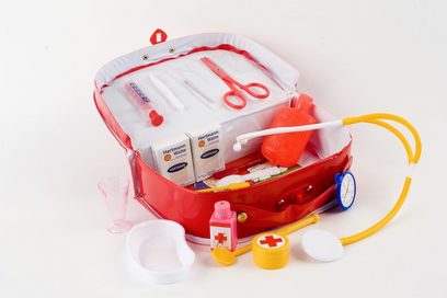 Auf einer hellen Oberfläche steht ein geöffneter Arzt-Spielkoffer mit medizinisch typischen Utensilien.