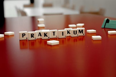  Spielsteine mit Buchstaben, die das Wort Praktikum bilden