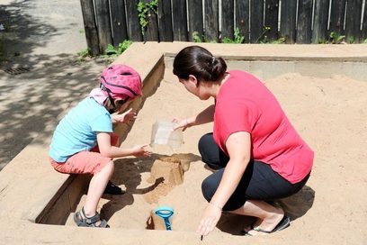 Mutter und Kind spielen im Sandkasten.
