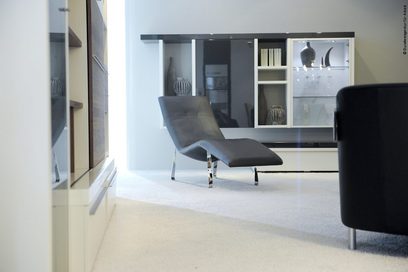 Eine Liege und ein Sitzmöbel vor zwei Schrankwänden in einer Ausstellung eines Möbelhauses